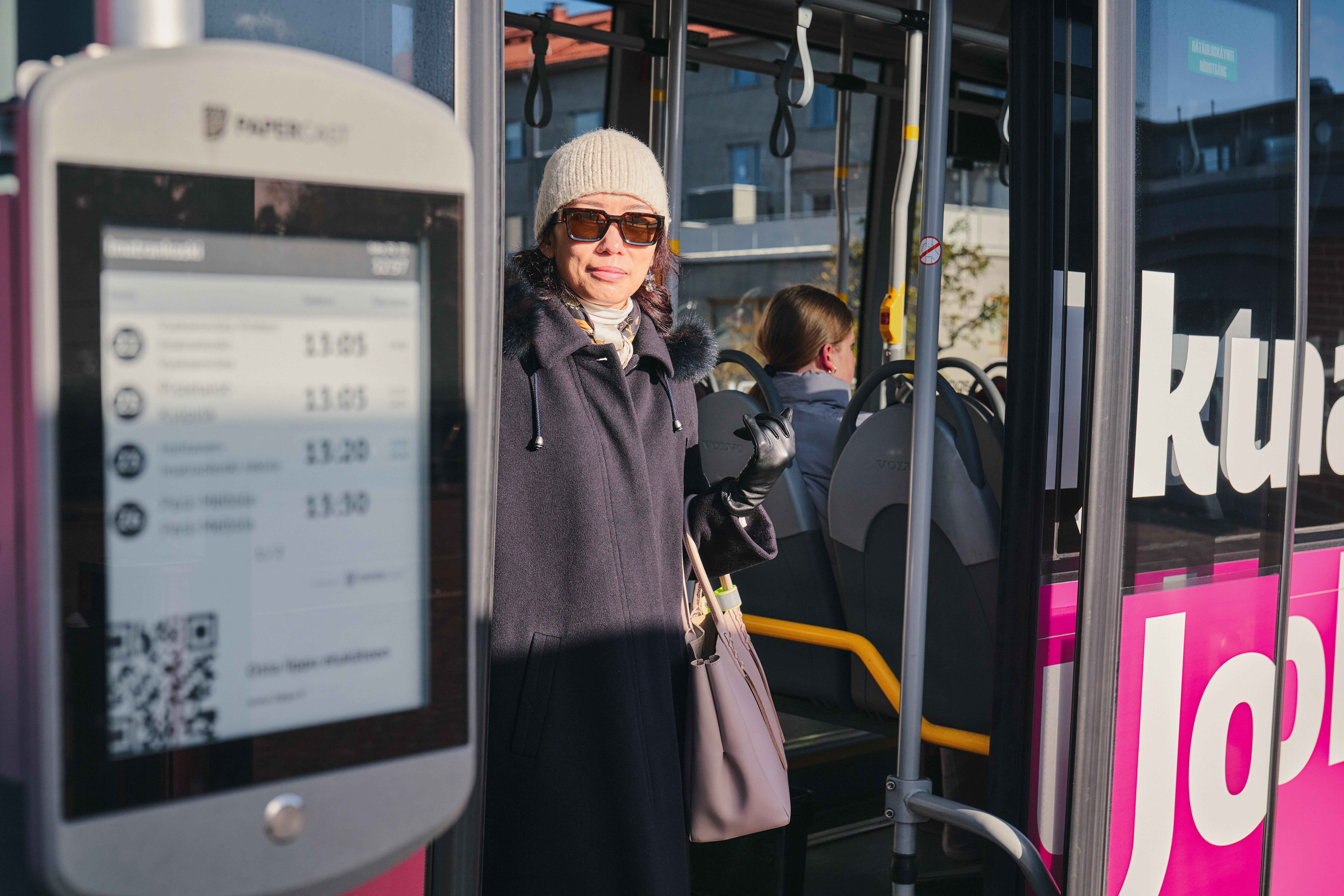Nainen talvivaatteissa Jouko-bussin ovella.